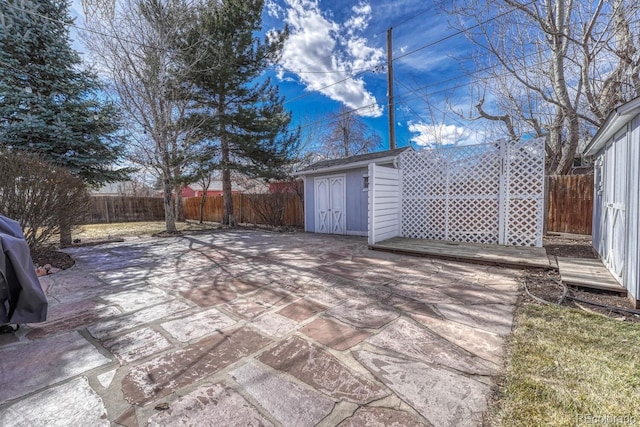 view of patio / terrace with a fenced backyard, a storage unit, and an outbuilding