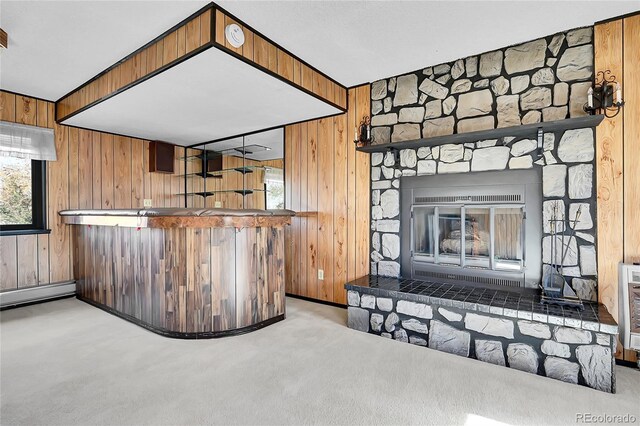 interior space with a fireplace, wood walls, light carpet, and a baseboard heating unit