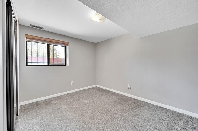 empty room featuring carpet and a textured ceiling