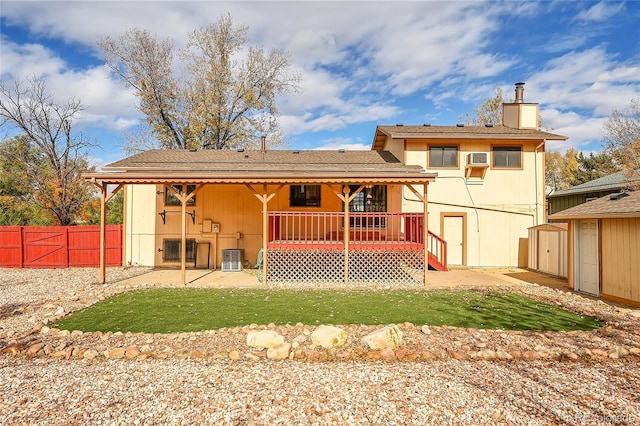 back of house with a lawn, a wall mounted AC, cooling unit, and a storage shed