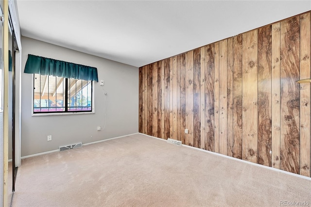 spare room with carpet and wood walls