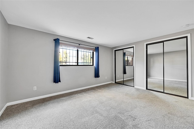 unfurnished bedroom with carpet floors and two closets