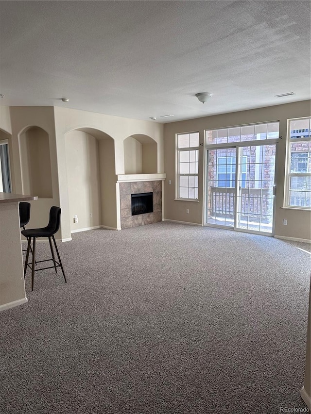 unfurnished living room with a fireplace, carpet floors, and a textured ceiling