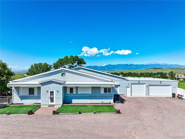 ranch-style home with a garage, a mountain view, and a front lawn