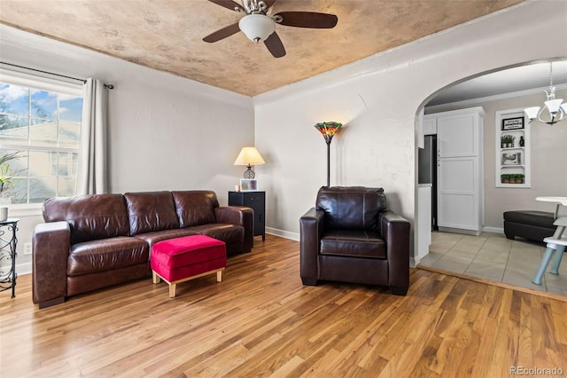 living room with ceiling fan with notable chandelier and light hardwood / wood-style flooring