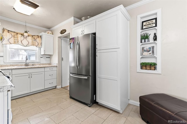 kitchen featuring ornamental molding, sink, white cabinets, and stainless steel refrigerator