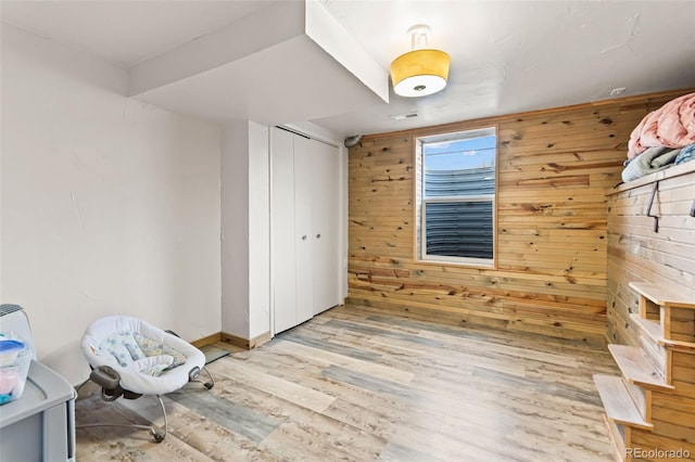 unfurnished bedroom featuring wooden walls, a closet, and light wood-type flooring