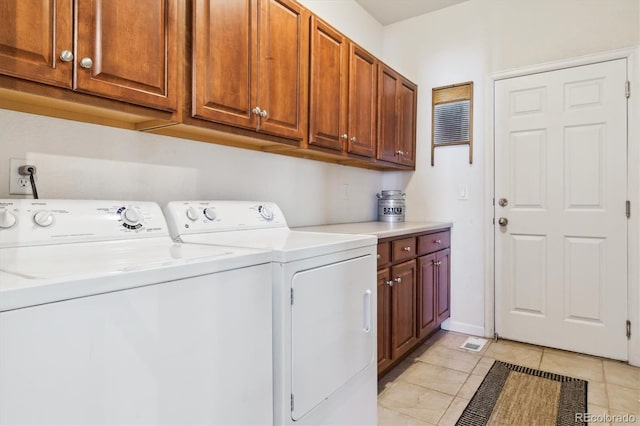 clothes washing area with cabinets, light tile patterned floors, and washing machine and dryer