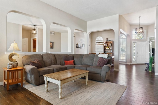 living room with dark wood-type flooring and a notable chandelier