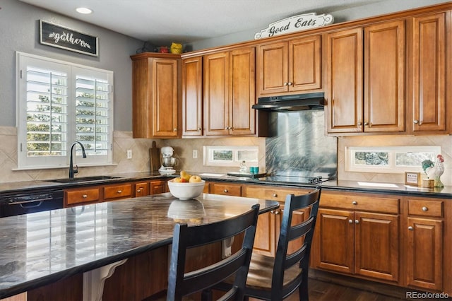 kitchen featuring decorative backsplash, dark hardwood / wood-style flooring, black appliances, sink, and dark stone countertops