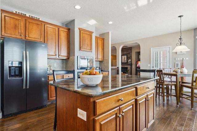 kitchen featuring refrigerator with ice dispenser, decorative light fixtures, a center island, and tasteful backsplash