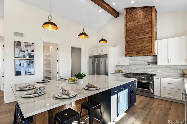 kitchen featuring white cabinets, beamed ceiling, high end appliances, and a large island