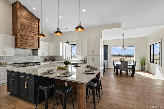 kitchen with white cabinets, pendant lighting, a large island, and hardwood / wood-style floors