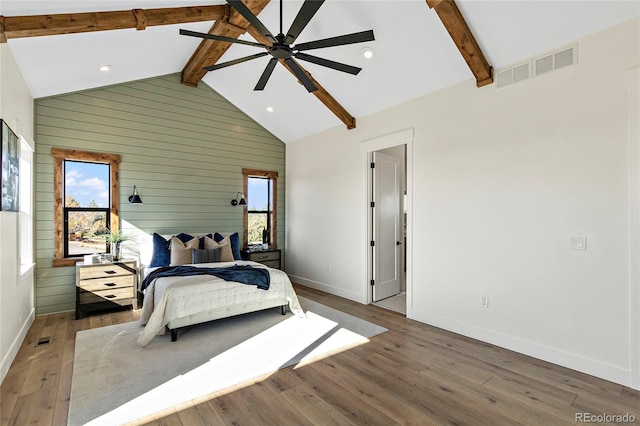 bedroom with dark hardwood / wood-style floors, beam ceiling, and multiple windows