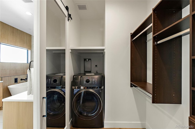 clothes washing area featuring a barn door and washing machine and clothes dryer