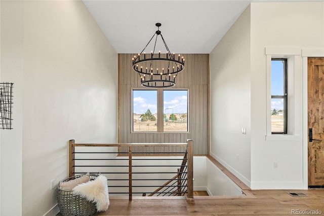 stairway with a chandelier, wood-type flooring, and vaulted ceiling