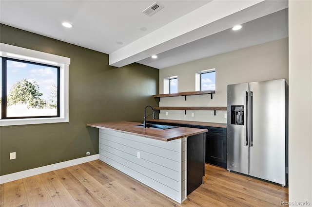 kitchen featuring a wealth of natural light, sink, stainless steel refrigerator with ice dispenser, and light hardwood / wood-style flooring