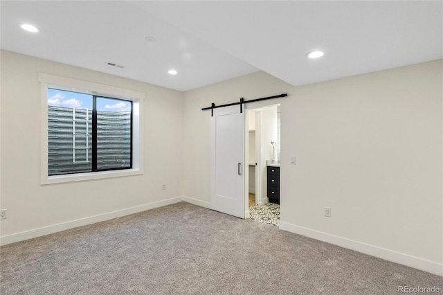 unfurnished bedroom with a barn door and light colored carpet