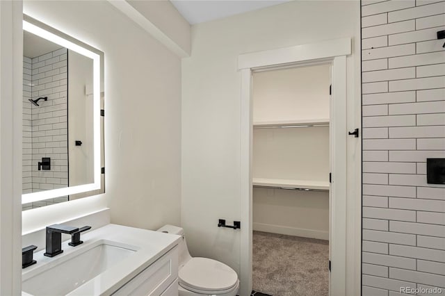 bathroom featuring tiled shower, vanity, and toilet