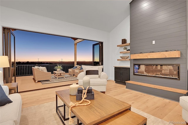 living room with a fireplace, light hardwood / wood-style floors, and vaulted ceiling