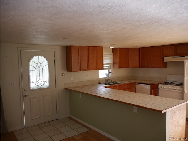 kitchen featuring kitchen peninsula, white appliances, sink, tile countertops, and light hardwood / wood-style floors