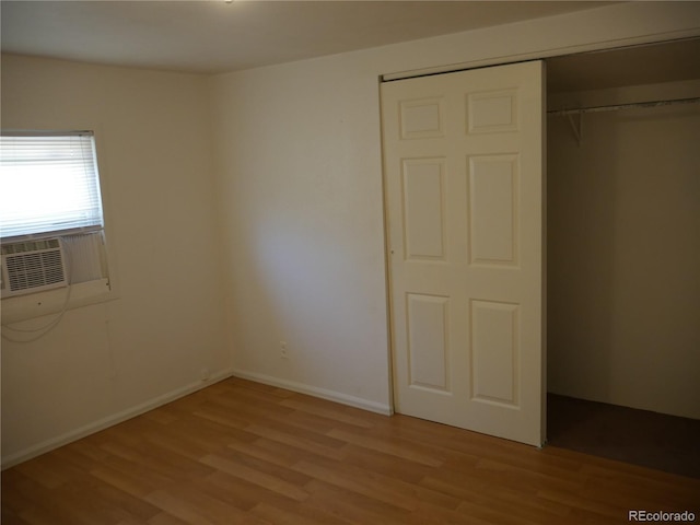 unfurnished bedroom with cooling unit, light hardwood / wood-style floors, and a closet