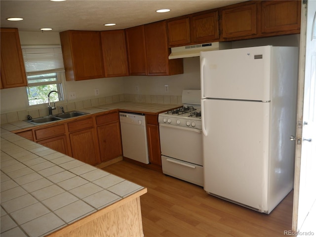 kitchen with white appliances, tile countertops, and sink