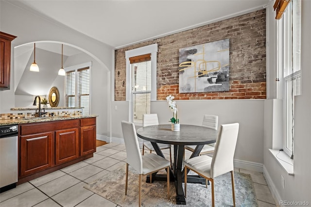 dining space featuring sink, light tile patterned flooring, and brick wall