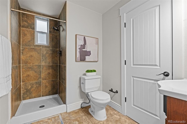 bathroom with vanity, toilet, and a tile shower