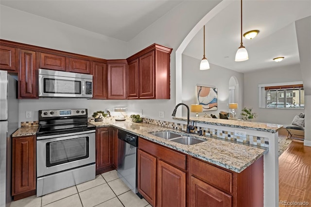 kitchen with sink, decorative light fixtures, kitchen peninsula, stainless steel appliances, and light stone countertops