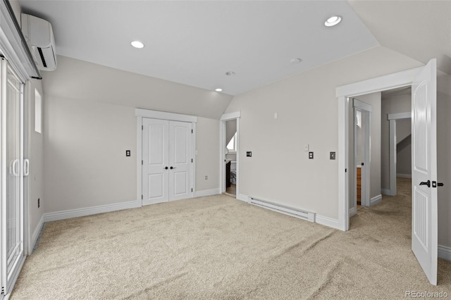 interior space featuring baseboard heating, vaulted ceiling, light carpet, and an AC wall unit