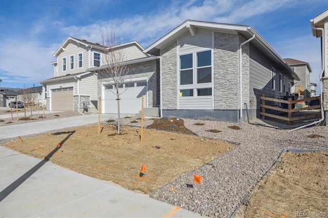 view of front of property with concrete driveway, fence, and stone siding