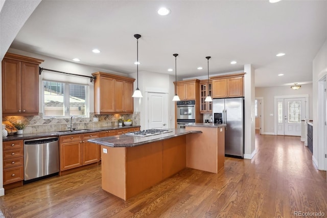 kitchen featuring sink, a kitchen island, dark wood-type flooring, and appliances with stainless steel finishes