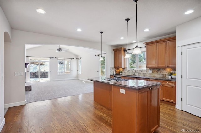 kitchen featuring tasteful backsplash, ceiling fan, dark wood-type flooring, decorative light fixtures, and a center island