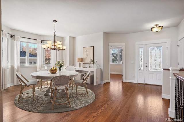 dining space with dark hardwood / wood-style floors and an inviting chandelier