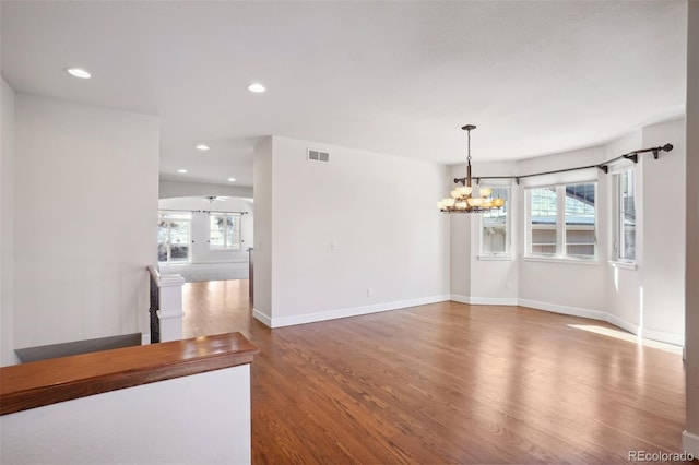 unfurnished room featuring an inviting chandelier and dark wood-type flooring