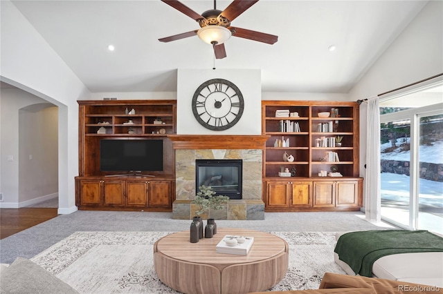 living room featuring a tile fireplace, ceiling fan, light hardwood / wood-style floors, and vaulted ceiling