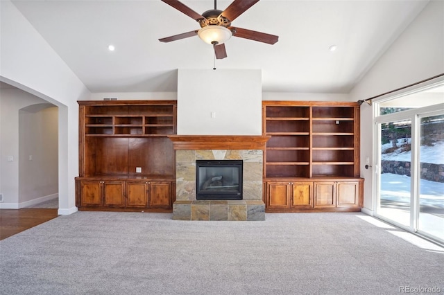 unfurnished living room featuring ceiling fan, light colored carpet, lofted ceiling, and a tiled fireplace