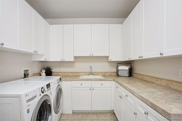 laundry room featuring washer and clothes dryer, cabinets, light tile patterned floors, and sink