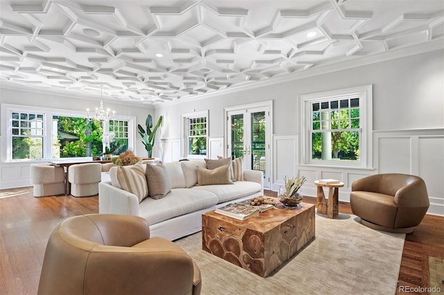 living room with an inviting chandelier, crown molding, light hardwood / wood-style floors, and a wealth of natural light