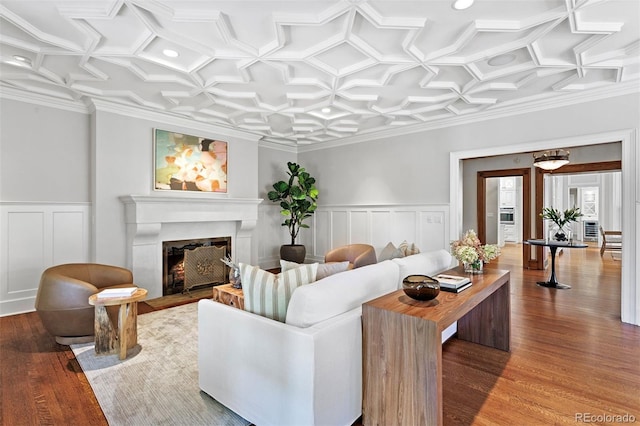 living room featuring coffered ceiling, ornamental molding, and hardwood / wood-style floors