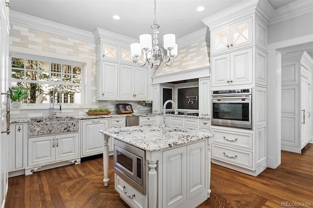 kitchen with appliances with stainless steel finishes, crown molding, white cabinetry, and a center island