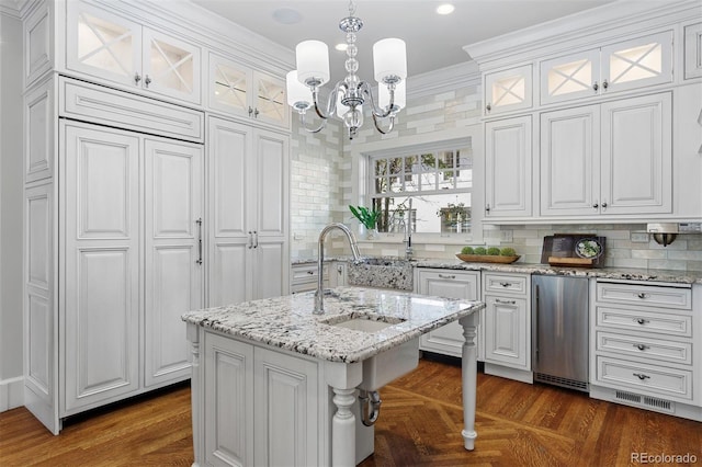 kitchen featuring white cabinets, decorative light fixtures, and a kitchen island with sink