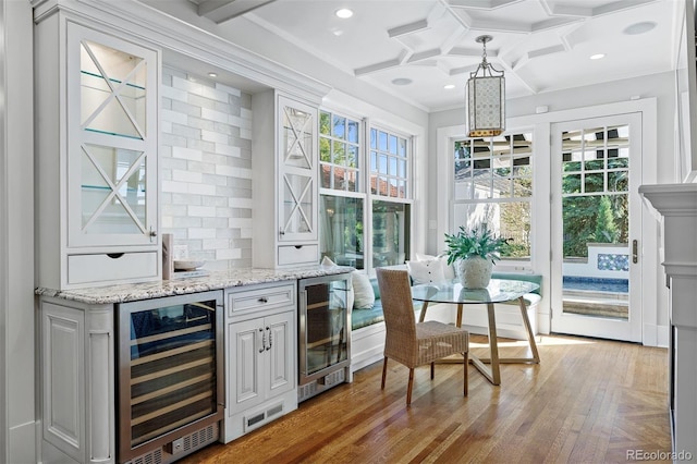 bar with wine cooler, hanging light fixtures, and a wealth of natural light