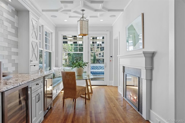 home office featuring a healthy amount of sunlight, coffered ceiling, beverage cooler, and wood-type flooring