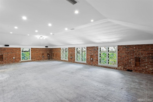 unfurnished living room featuring carpet, a fireplace, vaulted ceiling, and brick wall