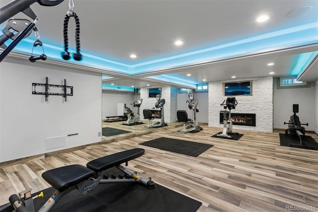 exercise room featuring a stone fireplace and hardwood / wood-style floors