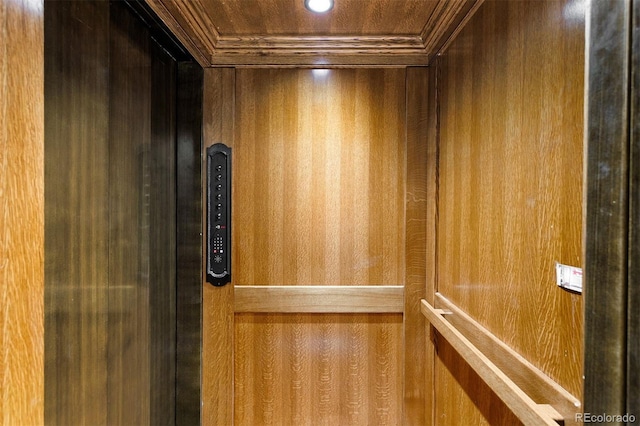 interior details with ornamental molding, wood walls, and elevator