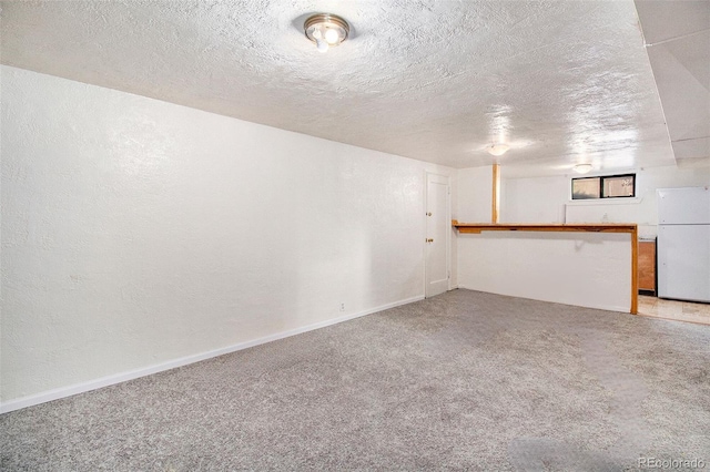 unfurnished room with light colored carpet, baseboards, and a textured ceiling
