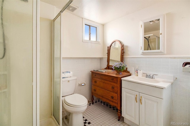 bathroom with tile walls, vanity, walk in shower, tile patterned flooring, and toilet